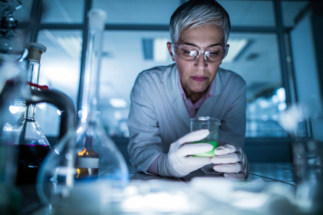 Mature chemist examining chemicals for her scientific research in laboratory. 
